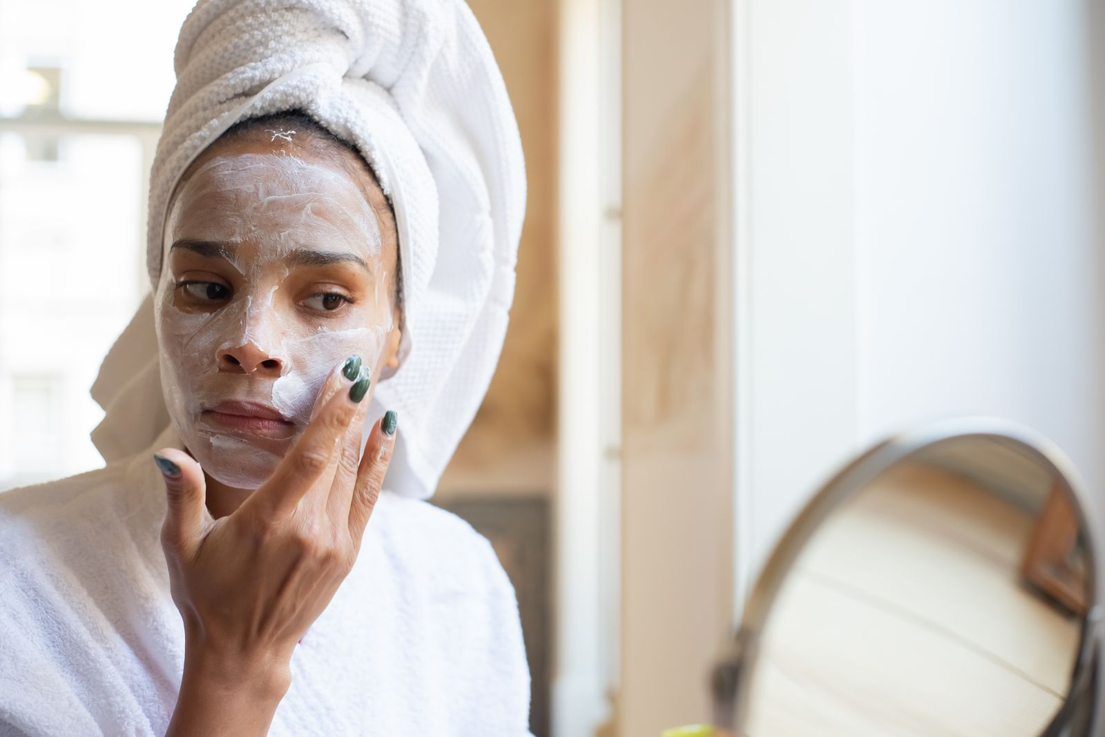 Woman applying skincare in bright natural light