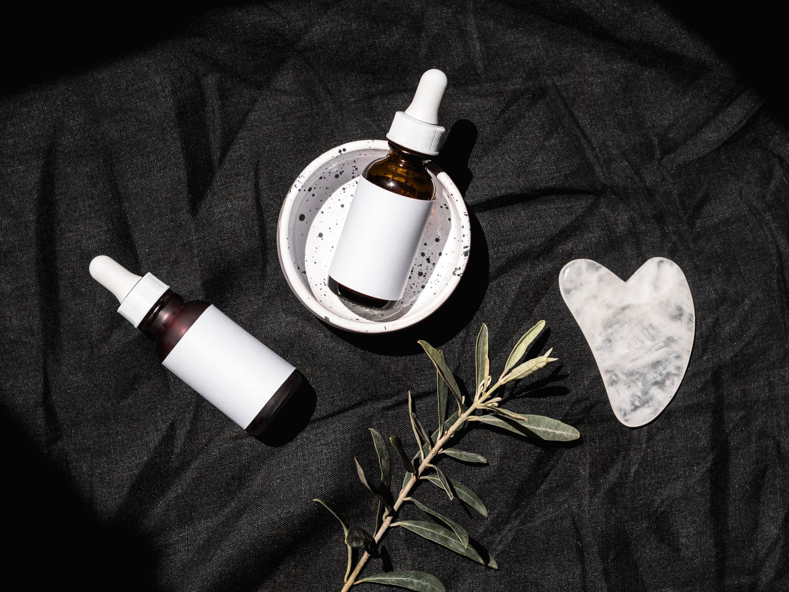 Unlabelled serum dropper bottles on dark linen